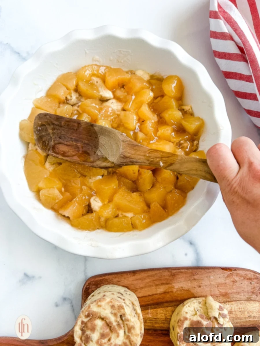 Smoothing the top of the dish with a wooden spoon, ensuring even distribution of ingredients before baking.