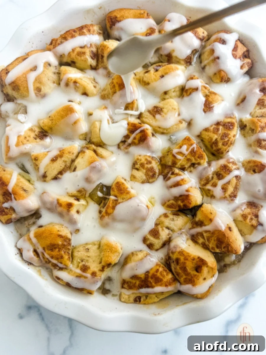 Drizzling white icing generously over warm, baked cinnamon rolls with apple pie filling.