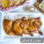 Platter of cooked chicken quarters on a white plate sprinkled with parsley flakes.