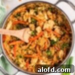 A pan of fried rice with veggies and chicken.