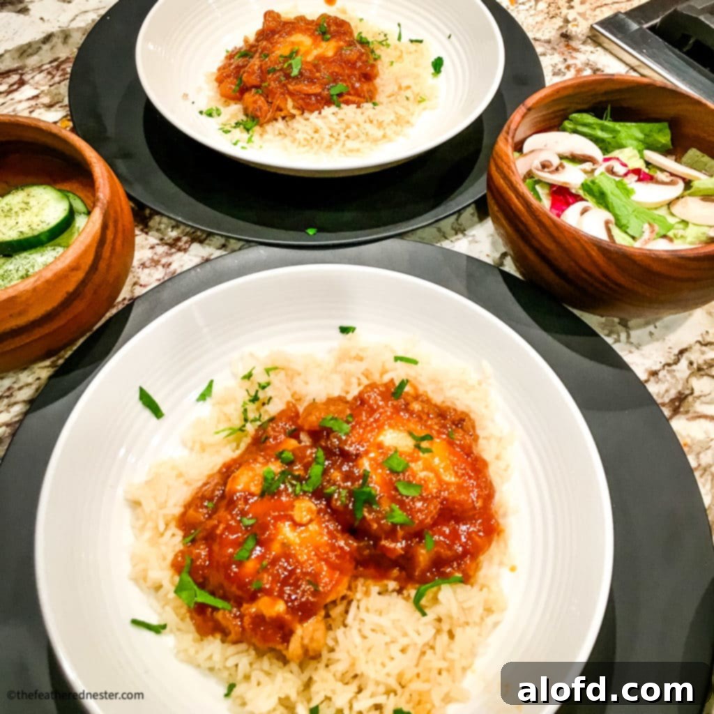 Two white plates with Huli Huli Chicken and two wooden bowls of vegetable sides.