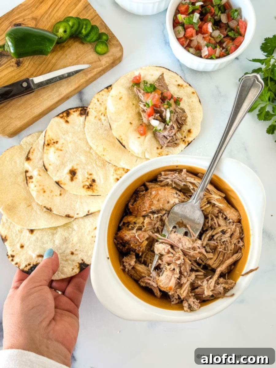 Assembling Mexican pulled pork and toppings on small corn tortillas.