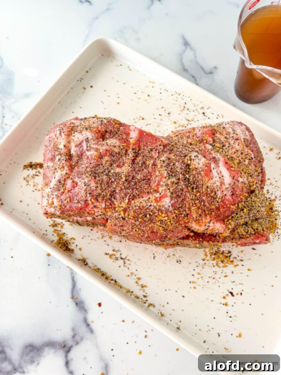 Uncooked Boston butt sprinkled with seasonings.