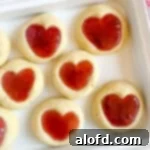 Cute heart-shaped jam cookies presented on a white platter.