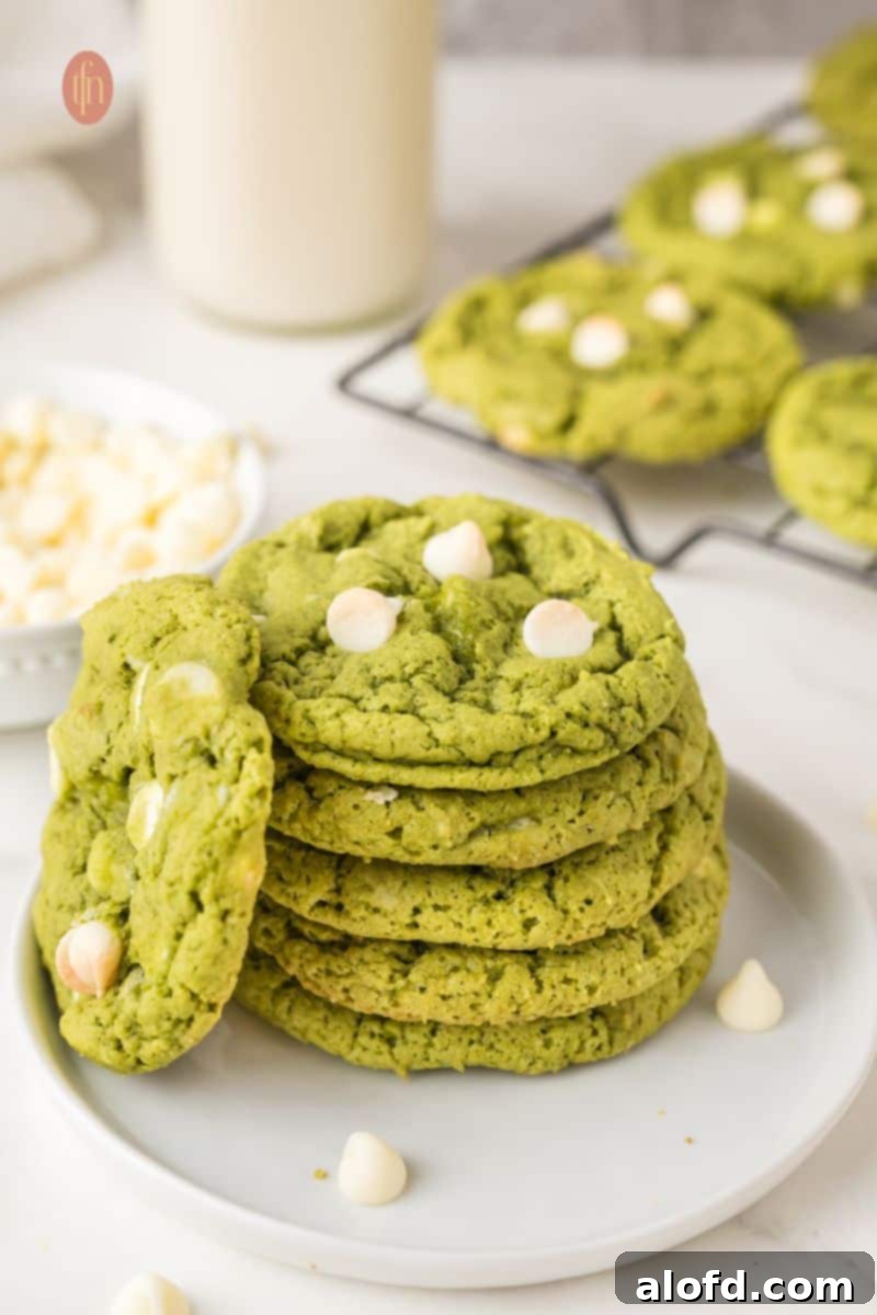 A plate of vibrant green matcha white chocolate cookies stacked artfully.