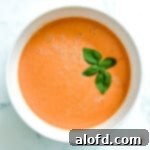 Lunchbox Hacks for Educators 6 A pristine white bowl brimming with rich tomato soup, elegantly garnished with a fresh sprig of basil.