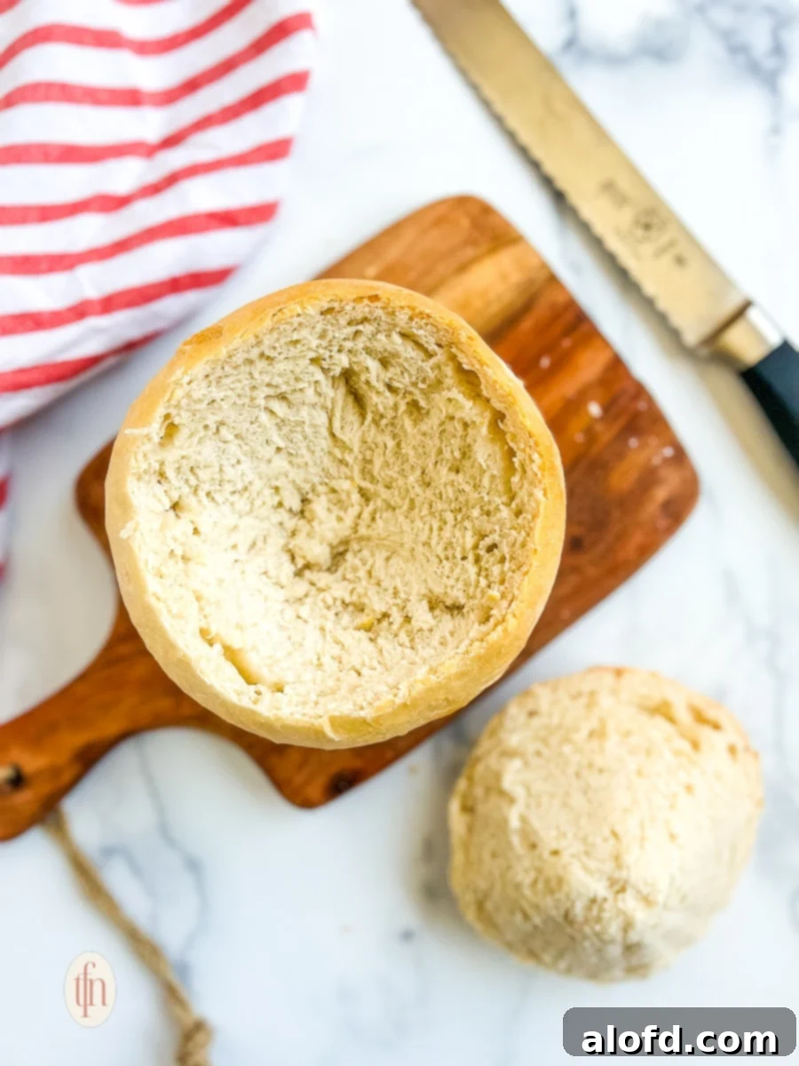 Harvest Bowls and Loaves 18 Round of bread with top removed on a cutting board next to a knife.
