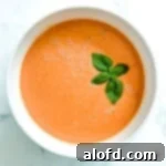 Harvest Bowls and Loaves 8 A white bowl filled with tomato soup and a sprig of basil on top.