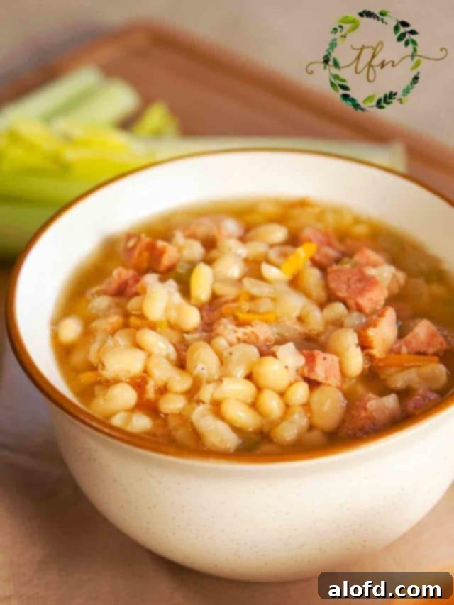 A white bowl of Instant Pot lima beans and ham ready to serve, garnished with fresh herbs.