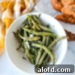 Steamed green beans in a bowl with a yellow gingham check linen napkin in the background.