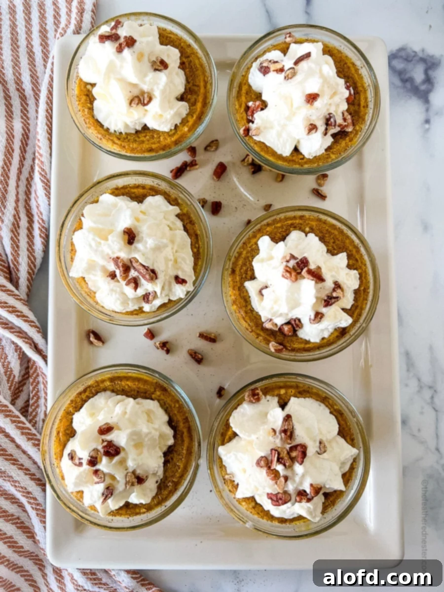 white serving plate with 6 cups of pumpkin custard with nuts and whipped cream on top.