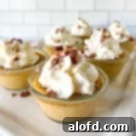 square photo of six cups of pumpkin custard and with whipped cream and nuts on top.