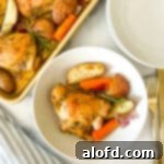 Sheet pan chicken thighs plated with roasted vegetables and fresh herbs.