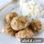 Turkey zucchini meatballs on a white plate next to a fork.
