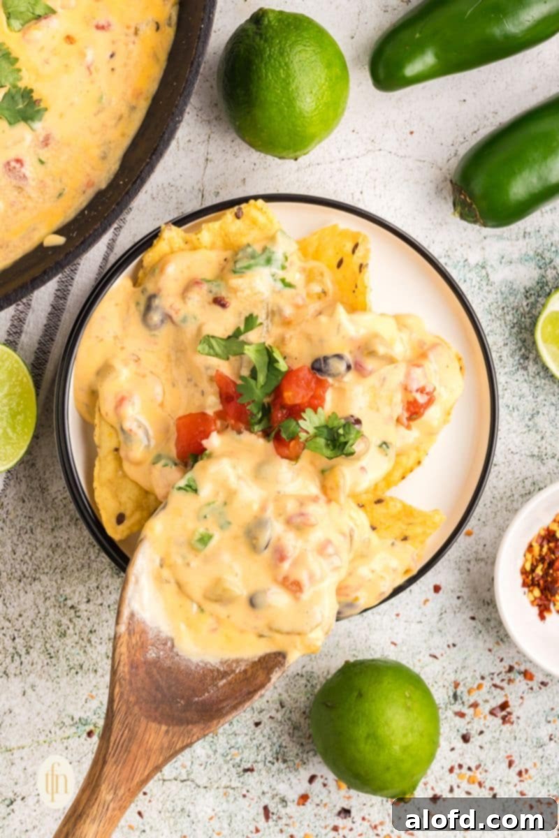 Nachos topping it with cheese sauce using a wooden spoon.