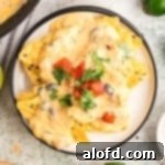 Nachos topped with cheese sauce and garnish on a round plate.