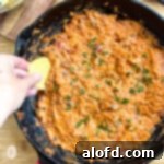 Game Day Grub 15 Dipping a tortilla chip into a cast iron skillet of smoked queso dip.