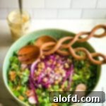 Game Day Grub 36 Green bowl of salad with a blend of kale and romaine salad with a jar of tahini dressing in the background.