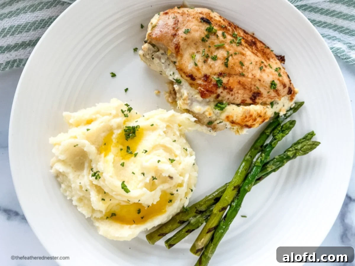 Game Day Grub 44 Cream cheese stuffed chicken breast on a plate with mashed potatoes and asparagus spears.