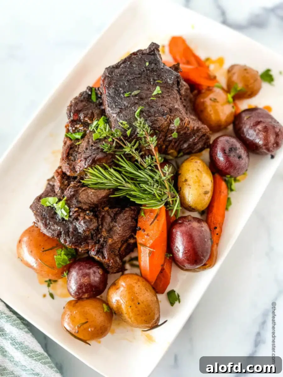 A beautifully presented platter of tender chuck pot roast, accompanied by hearty potatoes and sweet carrots.
