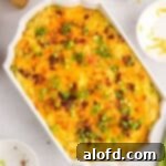 A tempting casserole dish filled with baked mashed potatoes, generously topped with crispy bacon and vibrant green onions.