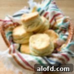 A basket artfully lined with a striped napkin, holding a tempting pile of flaky buttermilk biscuits.