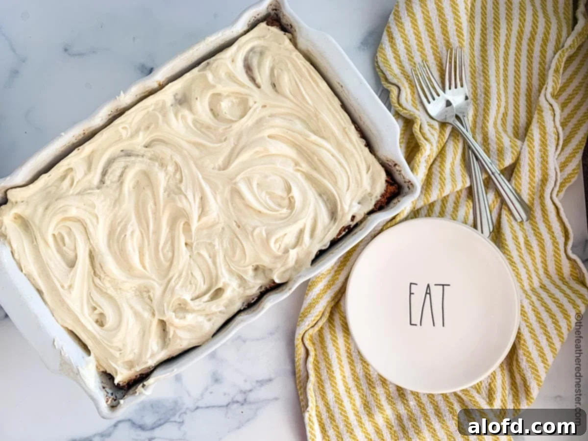 A pristine white pan containing a delicious sourdough cake, with small dessert plates and forks neatly arranged on top of a yellow and white kitchen towel nearby.