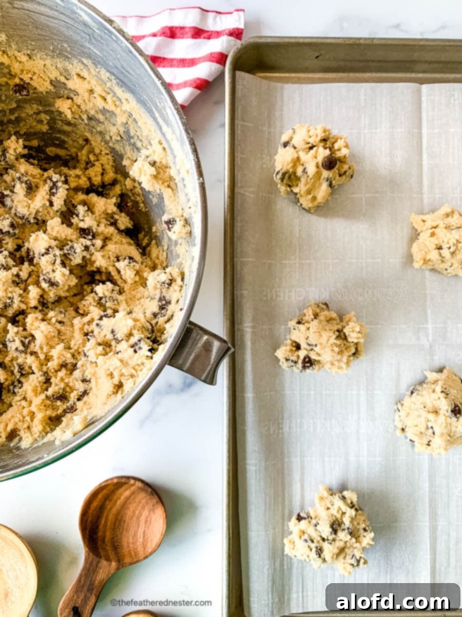Scoops of eggless cookie dough on a baking sheet next to the mixing bowl.
