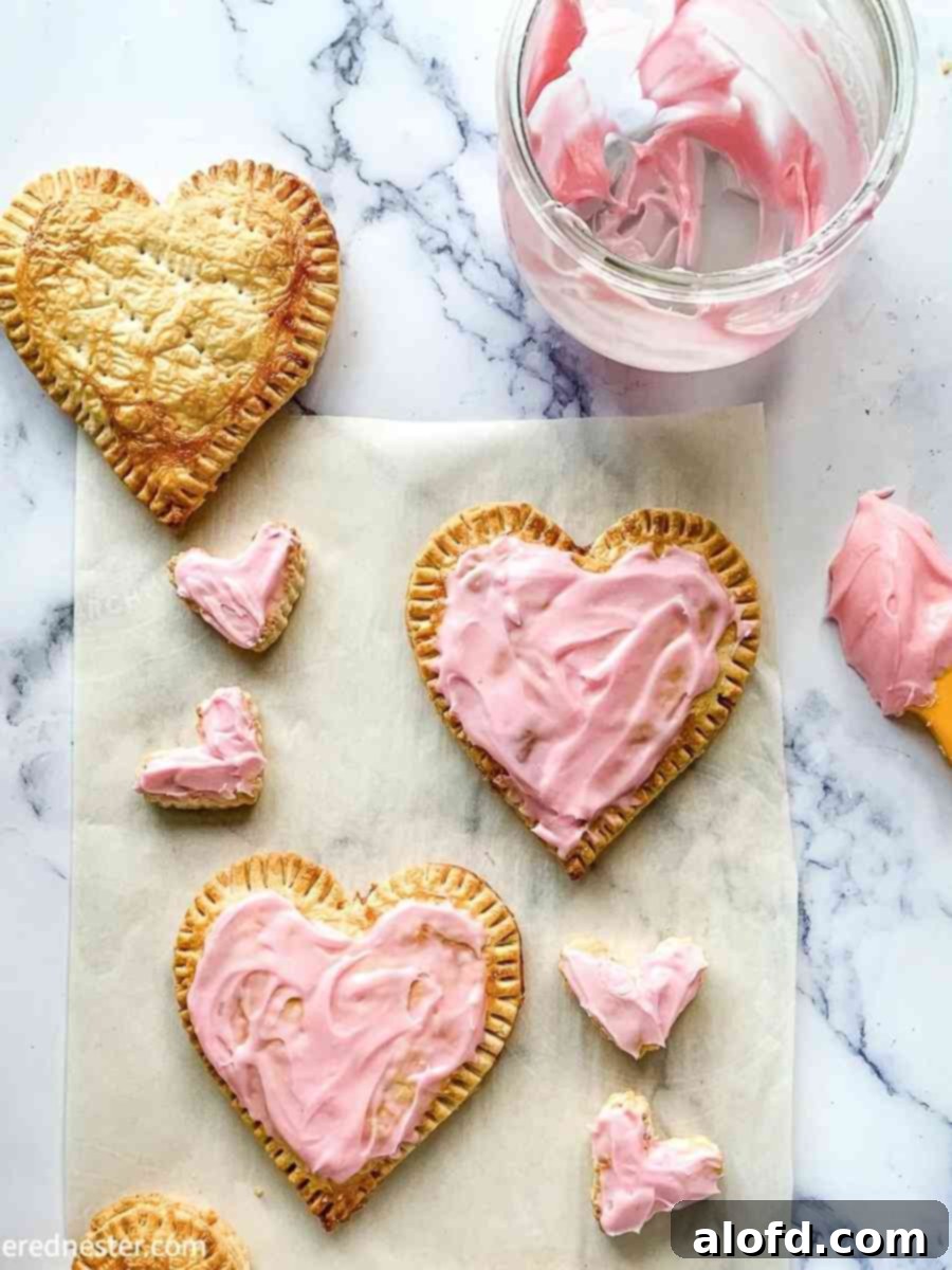Cupid's Confections 3 Frosted and unfrosted Valentine’s Day pop tarts, heart-shaped and filled with strawberry or cherry jam, ready to be enjoyed as a sweet treat.