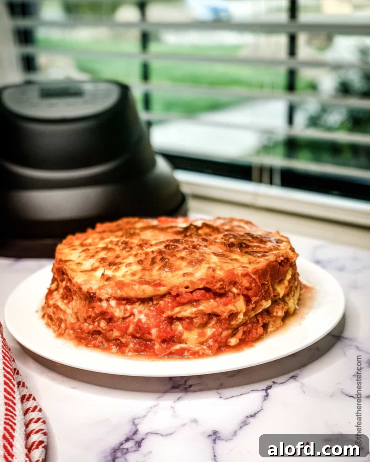 Delicious and easy Instant Pot ravioli lasagna cooling in a round springform pan, with an air fryer lid in the background.