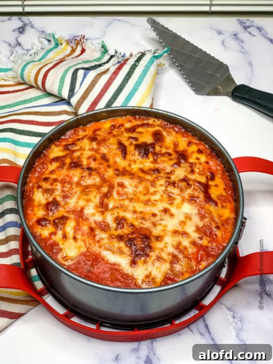 The pan of Instant Pot lasagna cooling with a serving spoon and striped napkin in the background, ready to be enjoyed.