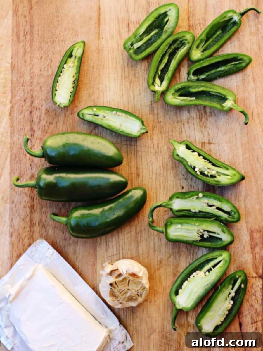 Ultimate Jalapeno Poppers 4 Detailed image of cleaning jalapeno peppers, showing seeds and membranes being removed.