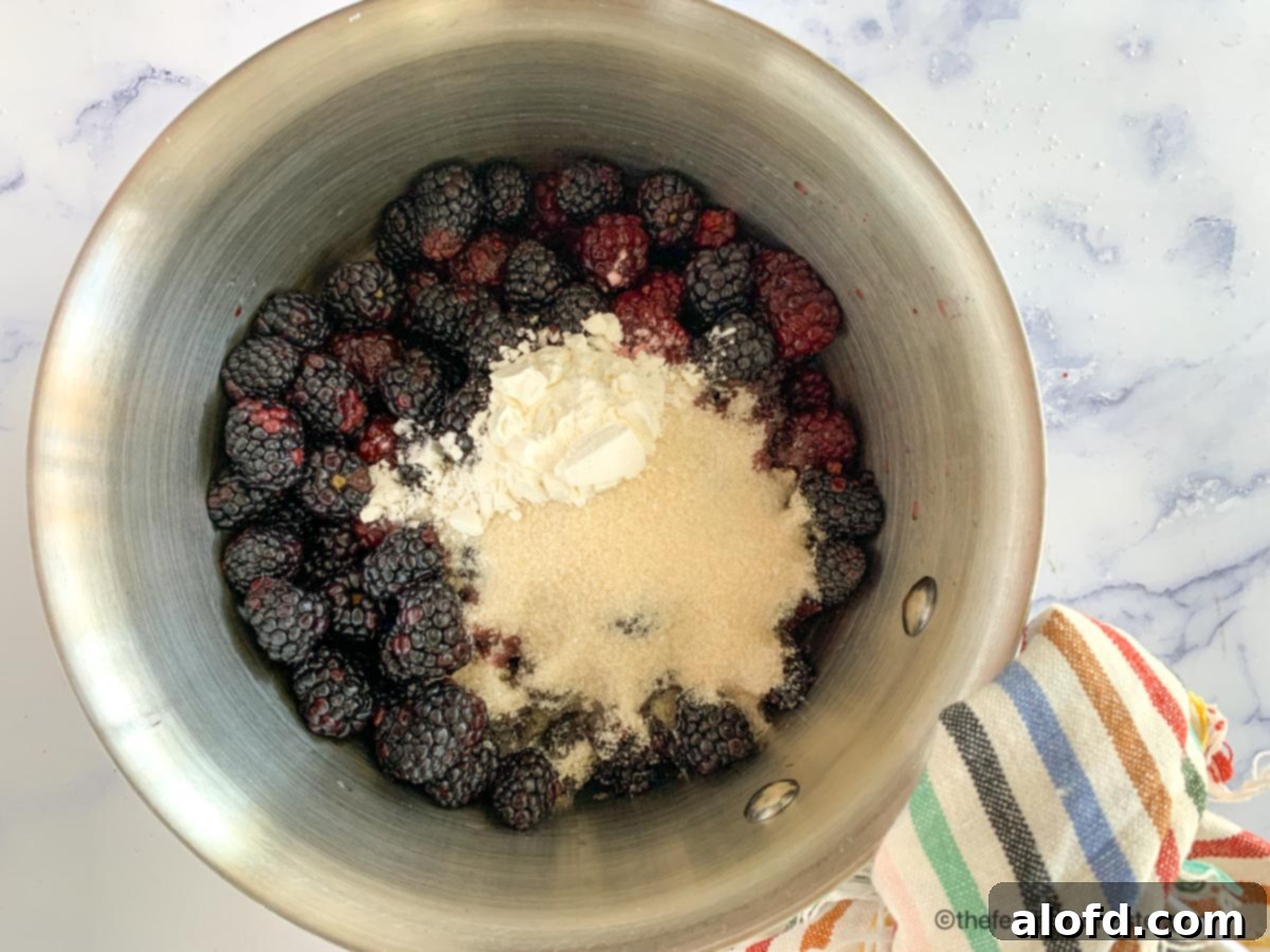 Effortless Bisquick Blackberry Bliss 5 A stainless steel saucepan with fresh blackberries, lemon juice, sugar, and cornstarch, ready to be heated on the stovetop.