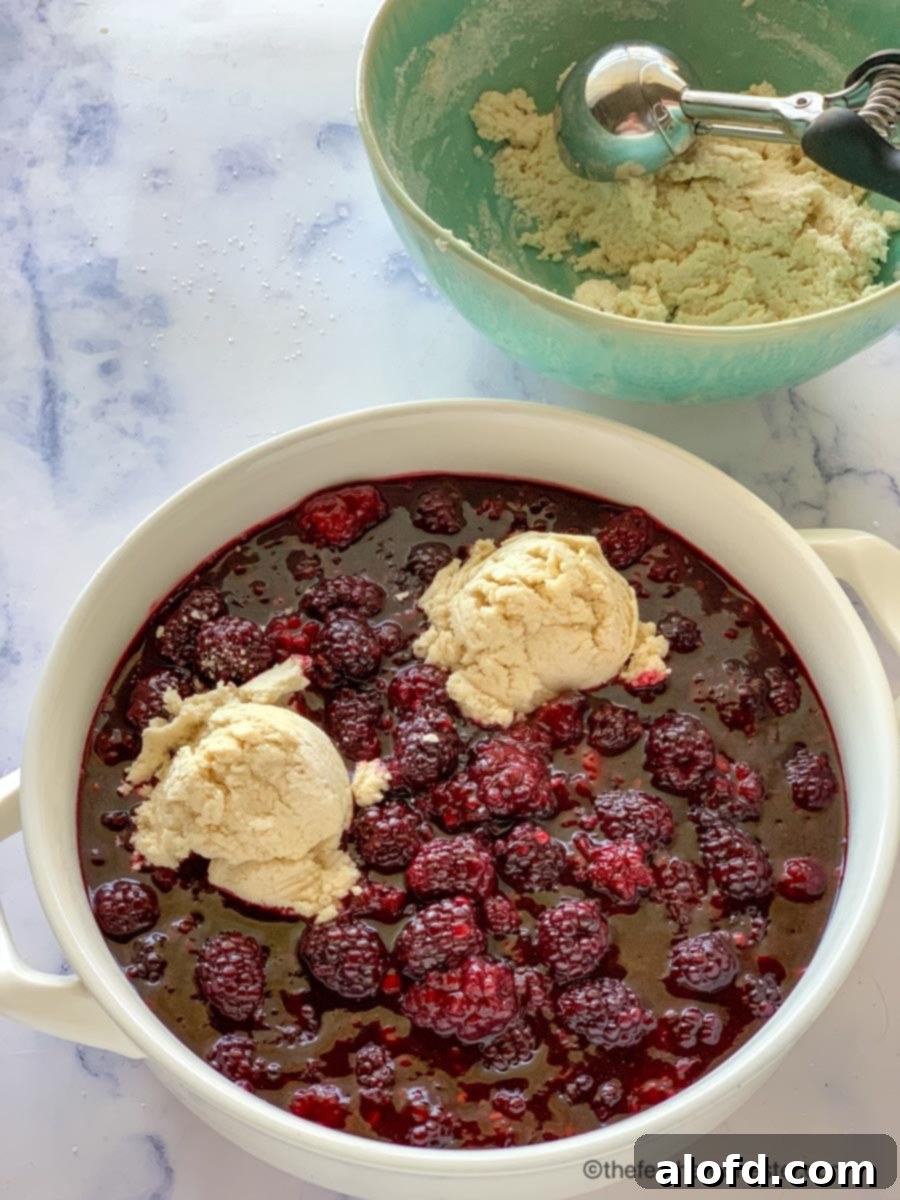 Effortless Bisquick Blackberry Bliss 6 Scooping biscuit topping over the blackberry cobbler recipe, ready for baking.