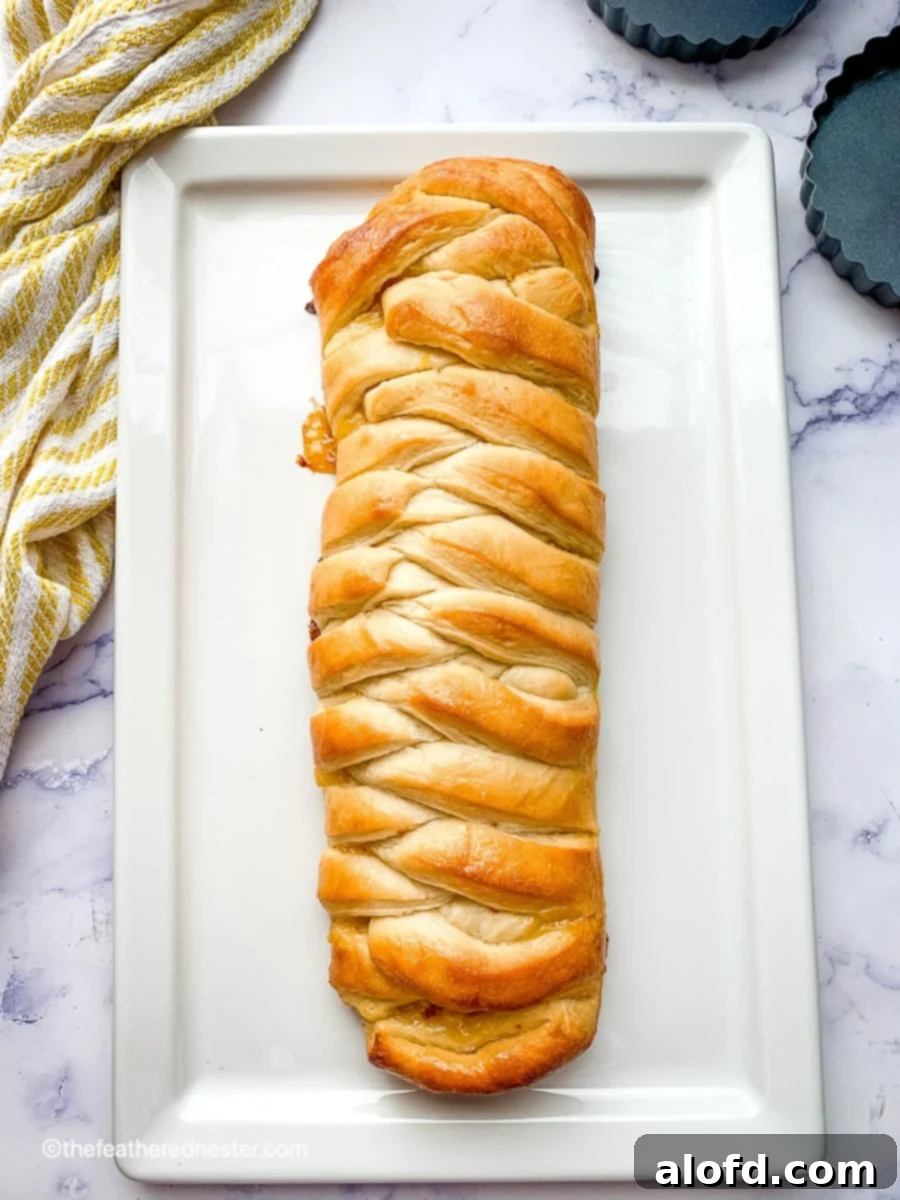Braided lemon bread on a white serving plate with a yellow and white striped towel, looking bright and inviting.