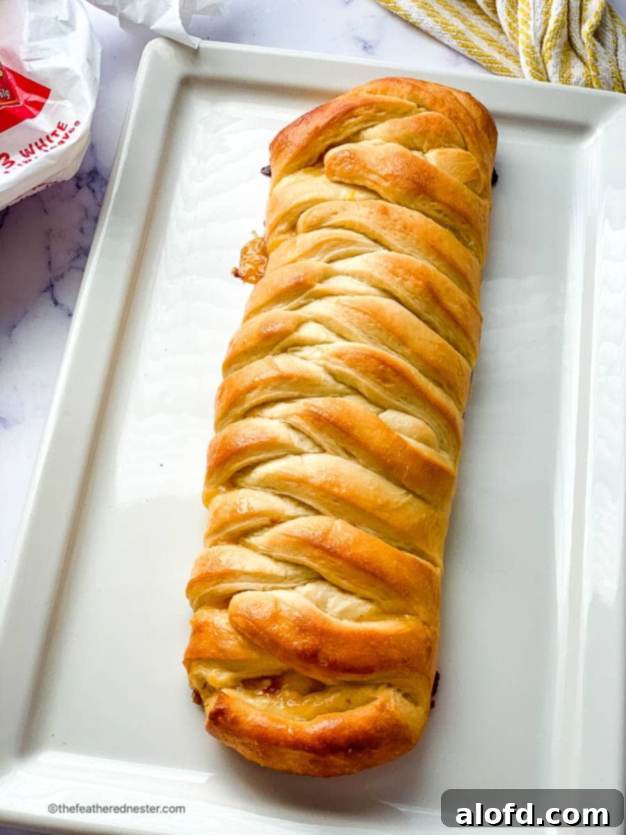 Lemon bread on a white rectangular plate, showcasing a perfect slice of the braided loaf.