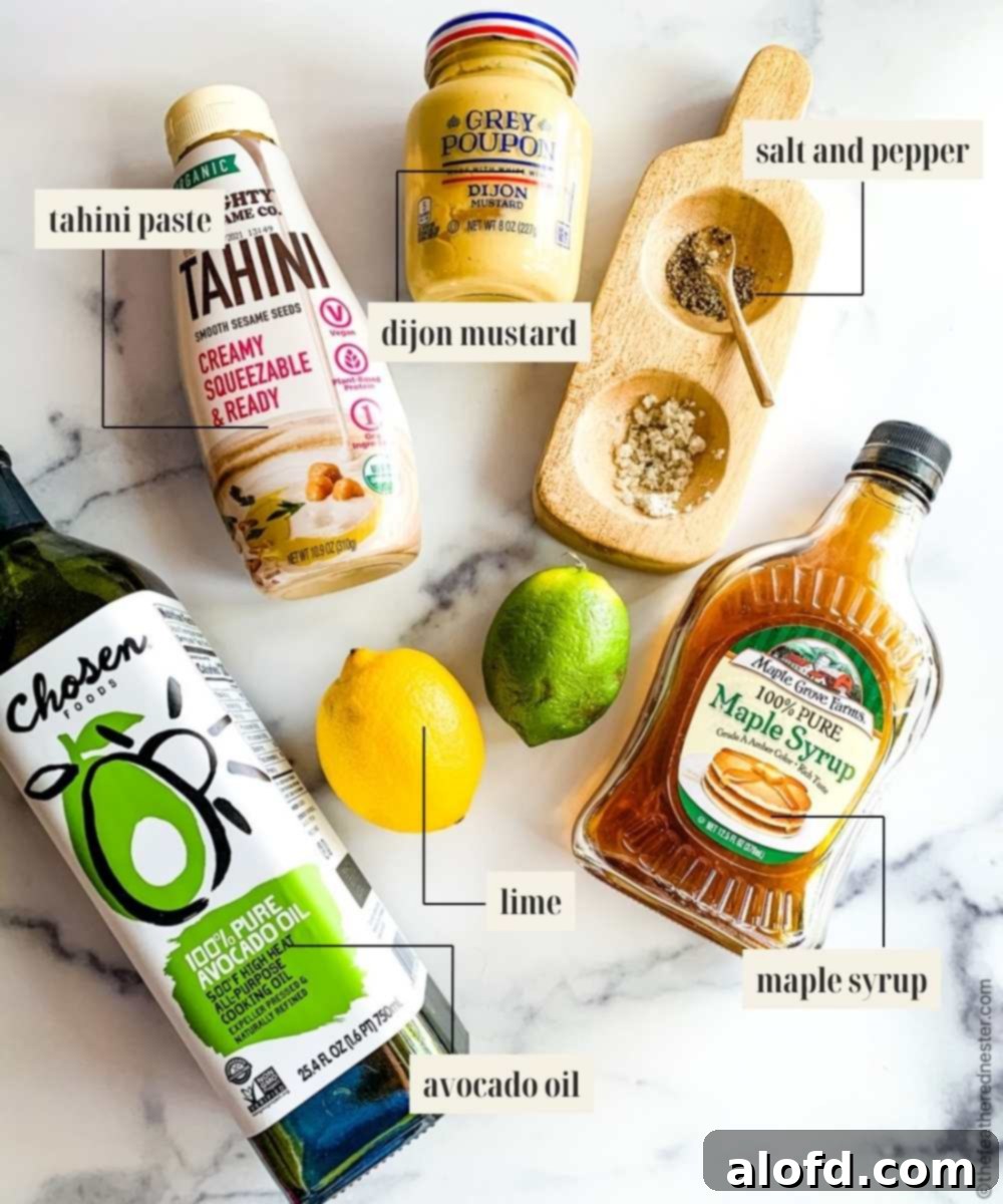 A close-up image showing individual ingredients for a creamy tahini dressing, including avocado oil, tahini paste, fresh lime, maple syrup, Dijon mustard, and cold water, arranged on a surface.