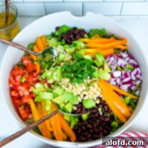 Vegan chopped cowboy salad in a white bowl, featuring colorful vegetables and beans.