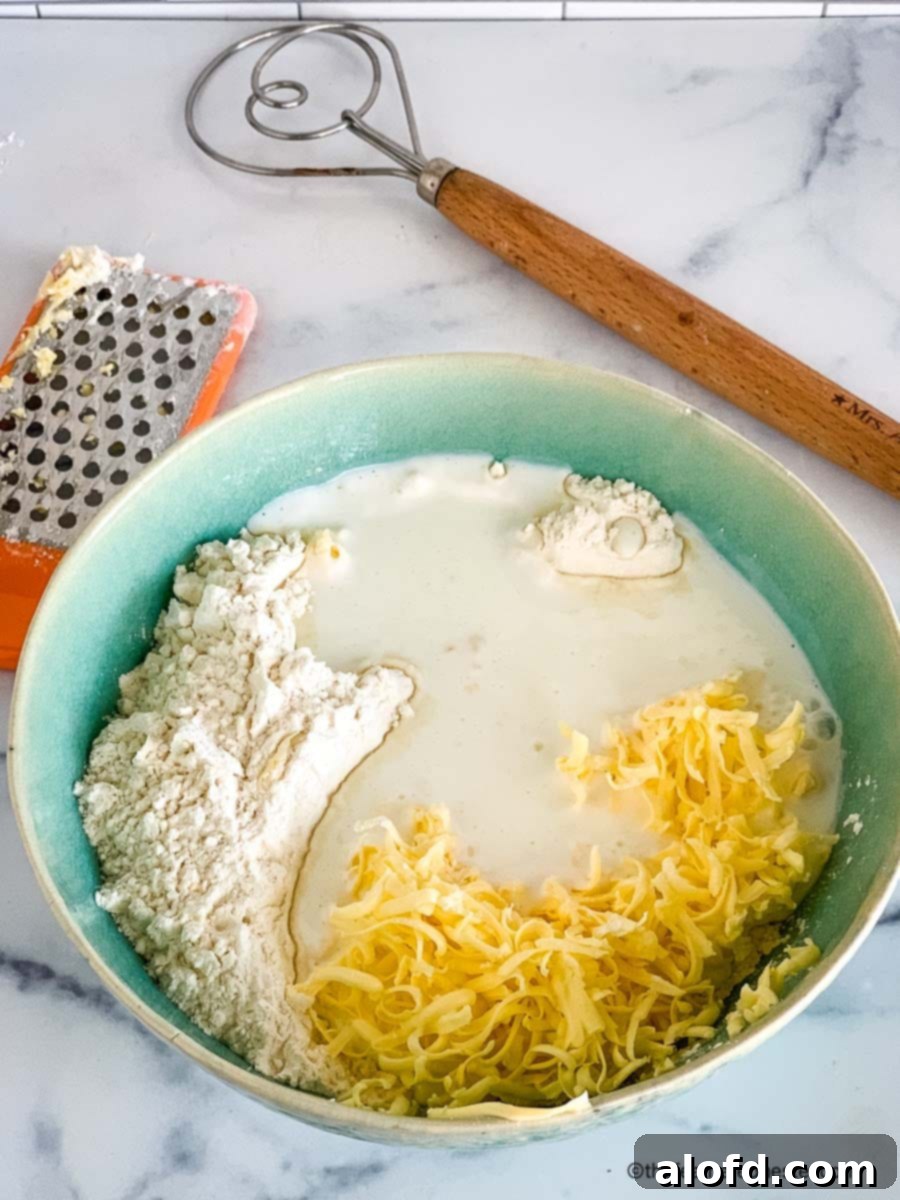 A bowl of biscuit ingredients with grater and dough whisk.