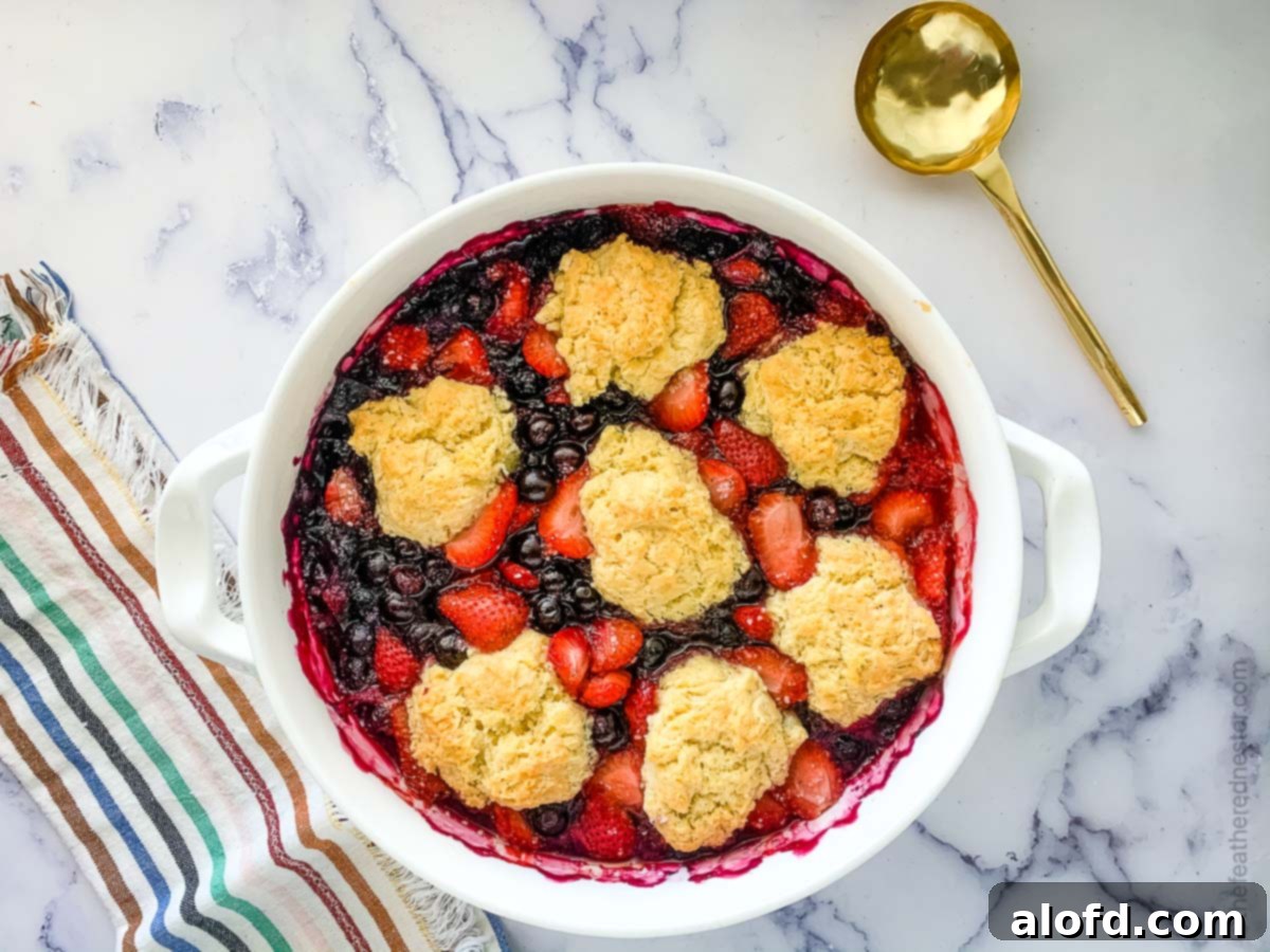 A fruit cobbler with strawberries and blueberries with biscuit topping.