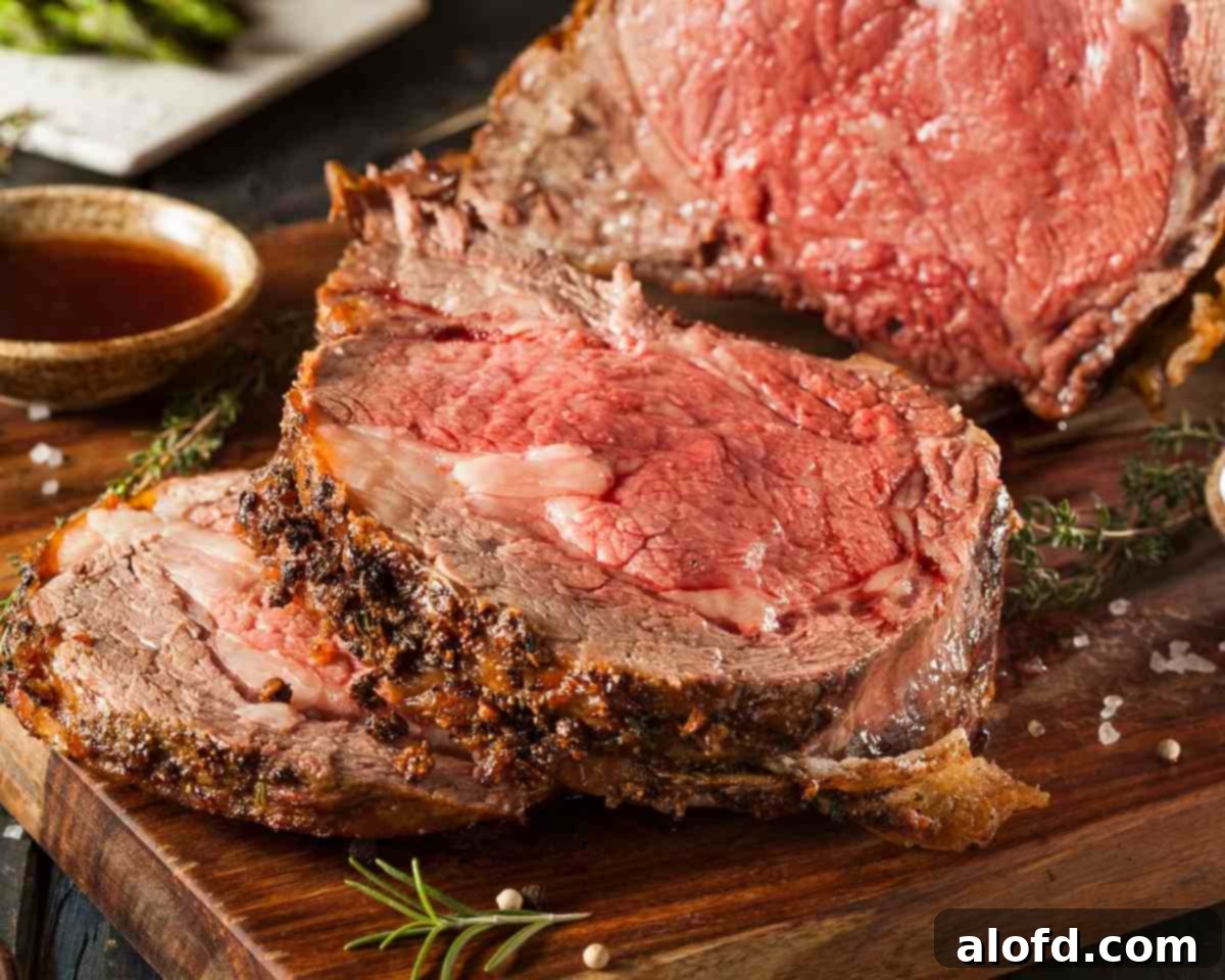 The Ultimate Prime Rib Roast 3 a plate of beef rib roast with mashed potatoes and asparagus with a cutting board showing a cut prime rib roast.
