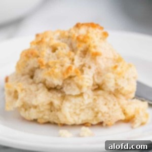 Homestyle Buttermilk Biscuits 11 A piece of a drop biscuit on a white plate, highlighting its flaky texture.