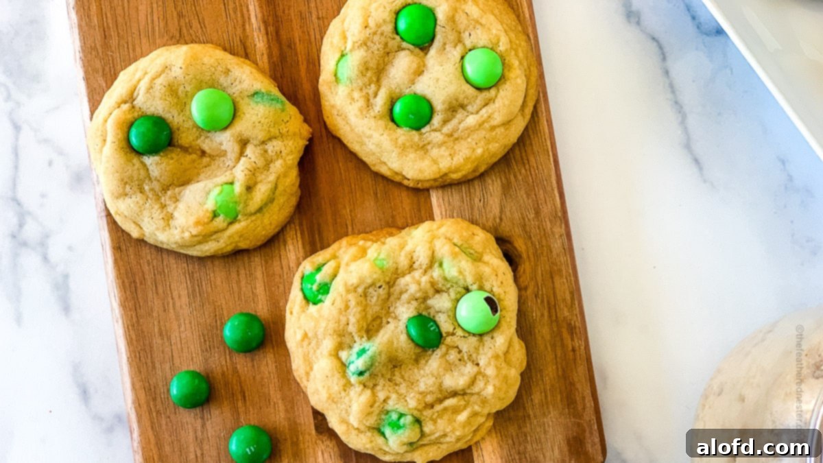Refreshing Mint Chocolate Indulgence 3 Green M&M cookies arranged neatly on a wooden serving board, ready for a festive gathering.