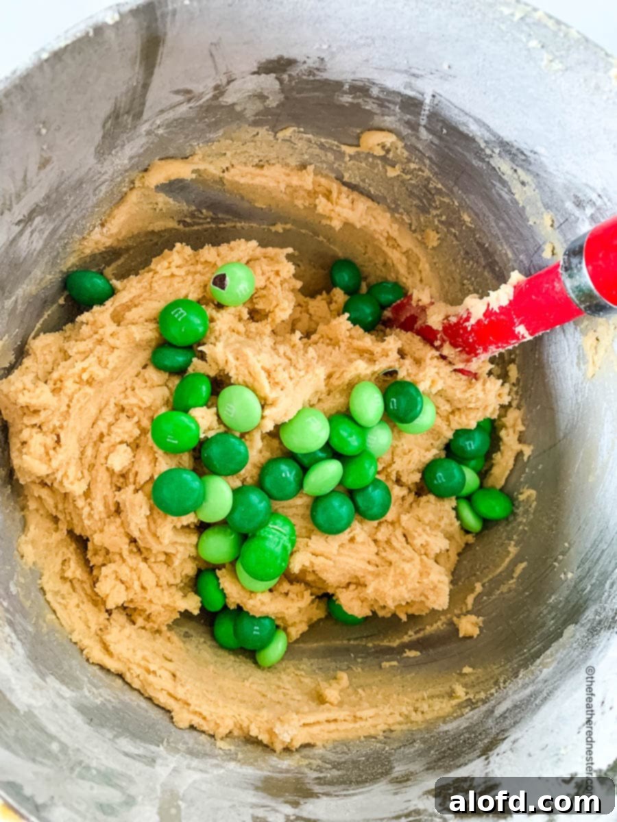 Refreshing Mint Chocolate Indulgence 5 A close-up of cookie dough being mixed with vibrant mint M&M candies in a bowl.