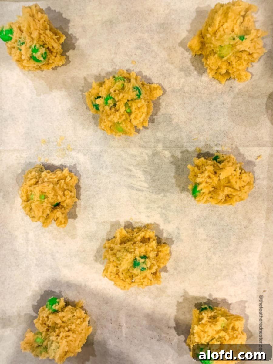 Refreshing Mint Chocolate Indulgence 6 Scoops of unbaked mint M&M cookie dough perfectly spaced on a parchment-lined baking sheet.