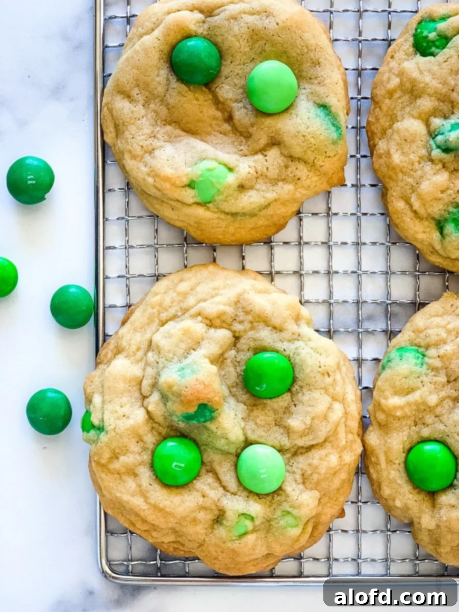 Refreshing Mint Chocolate Indulgence 8 A hand gently pressing mint M&M candies into the tops of warm, freshly baked cookies on a cooling rack.