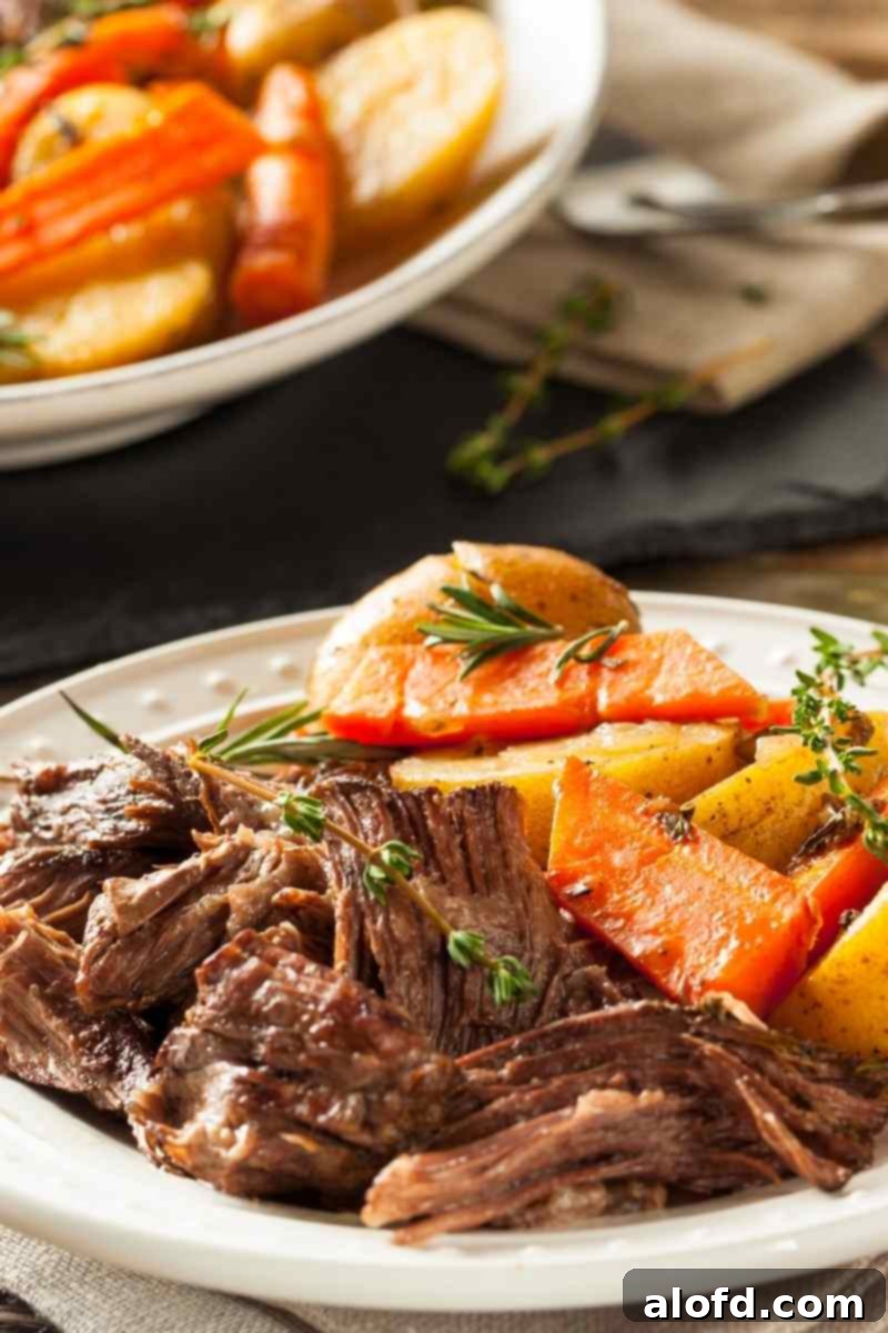Meltingly Tender Slow Cooker Chuck Roast 2 A delicious plate of fork-tender slow cooker pot roast with roasted potatoes and carrots, ready to be served for a hearty family dinner.