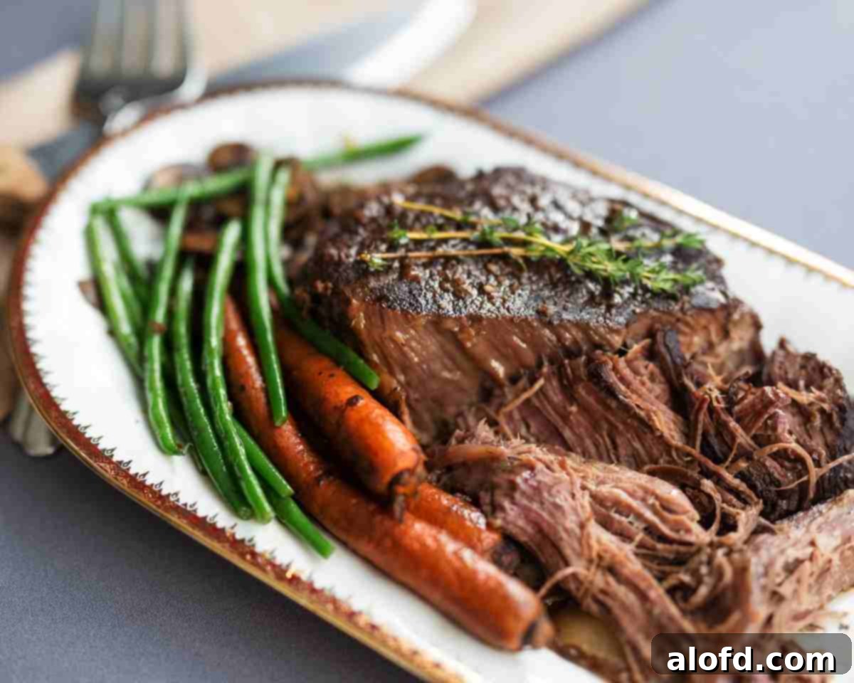 Meltingly Tender Slow Cooker Chuck Roast 3 A serving platter showcasing a succulent crockpot chuck roast with rich gravy, vibrant carrots, and tender green beans, inviting you to dig in.