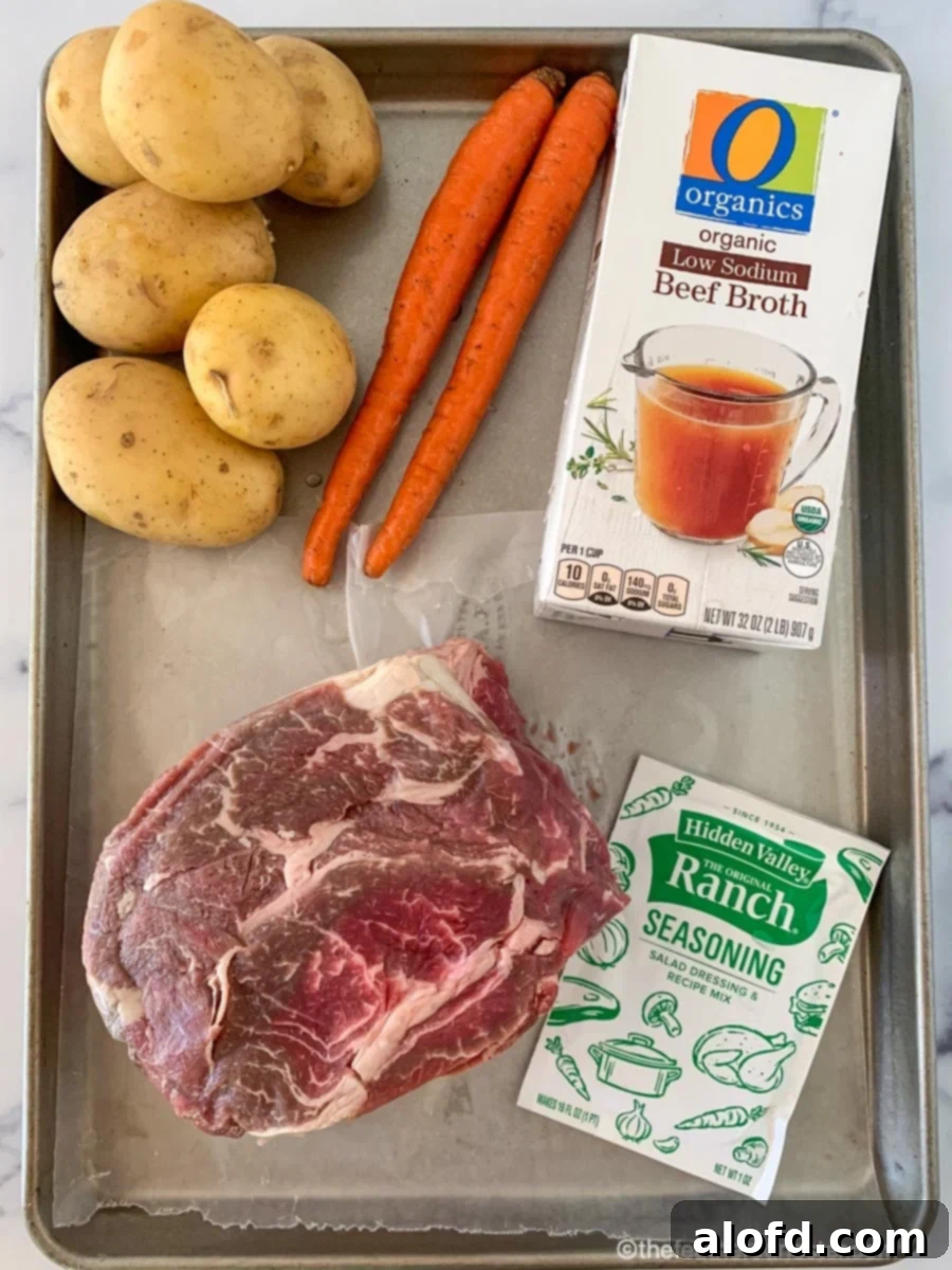 Meltingly Tender Slow Cooker Chuck Roast 4 Key ingredients for crockpot chuck roast: a raw chuck roast, a packet of dry ranch seasoning mix, low-sodium beef broth, russet potatoes, and fresh carrots, all ready for the slow cooker.