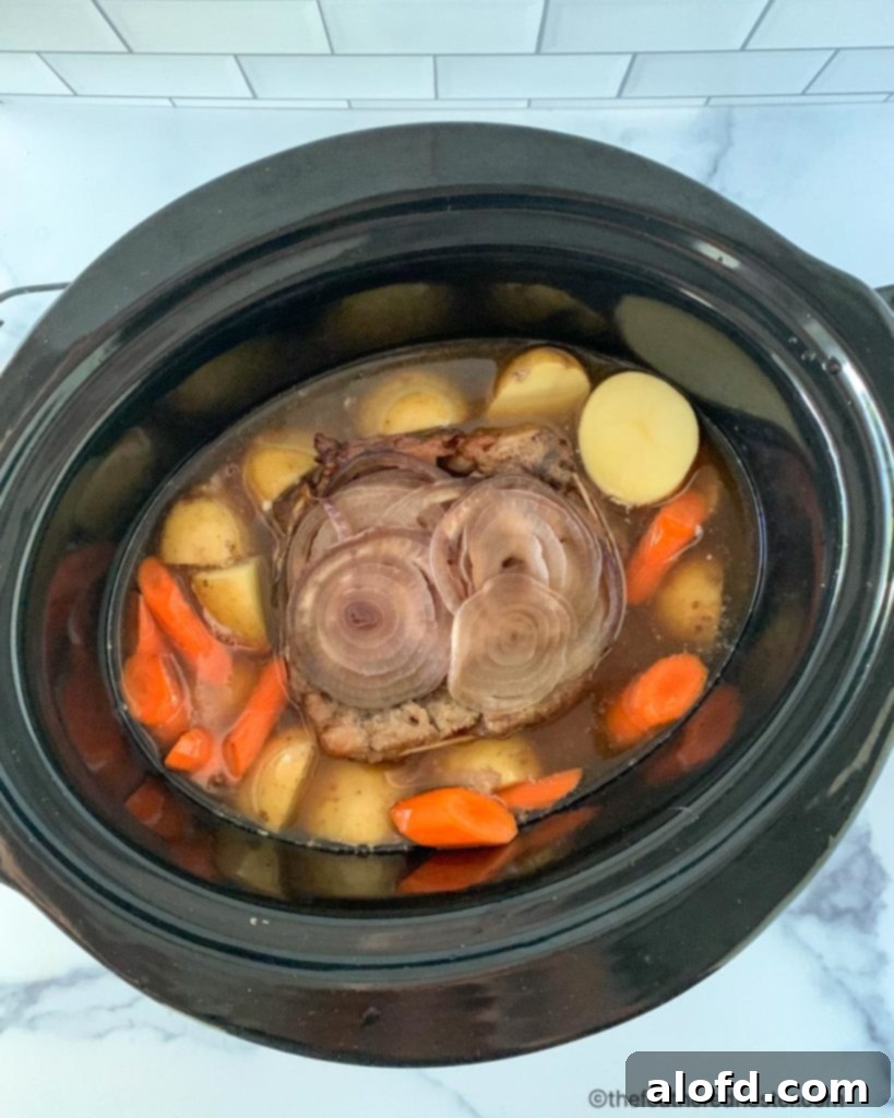 Meltingly Tender Slow Cooker Chuck Roast 6 Potatoes and carrots being added to a slow cooker with cooking chuck roast, during the final two hours of cooking to ensure they are perfectly tender.